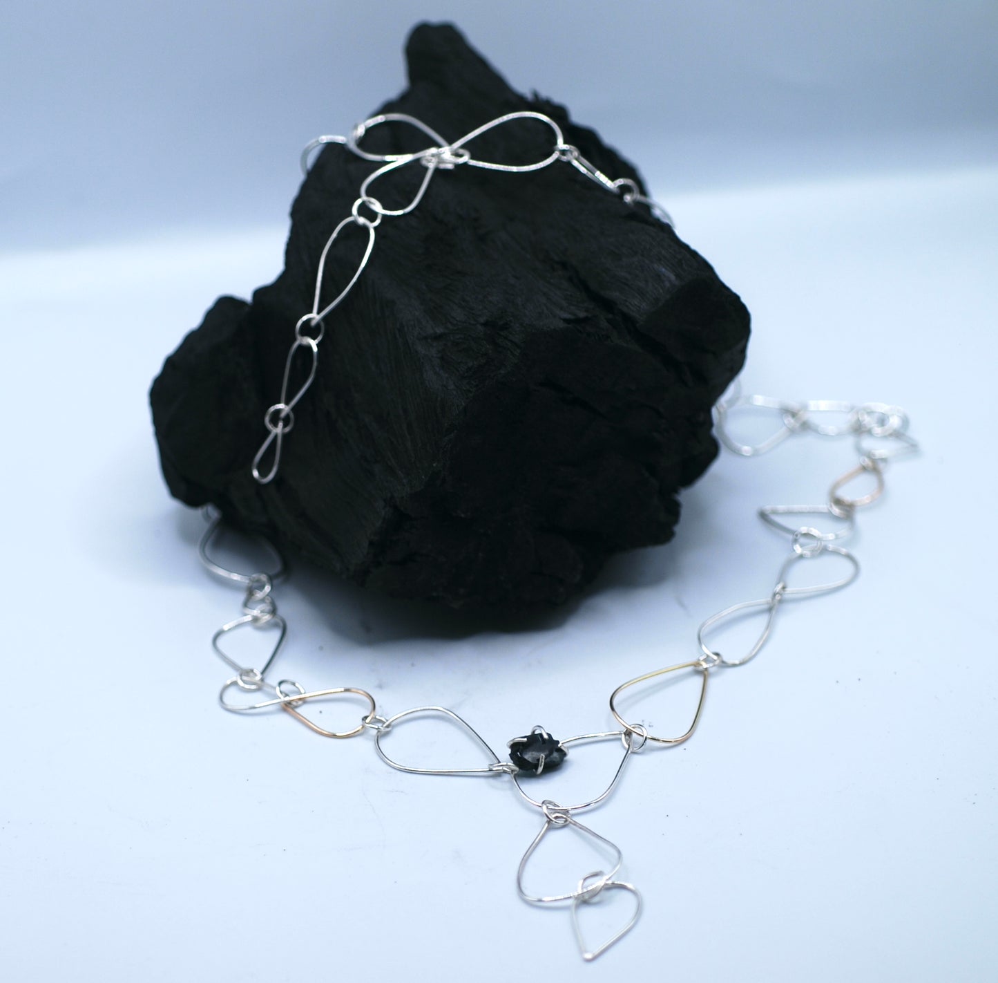 Necklace with siver and golden chains and a small tourmaline gemstone
