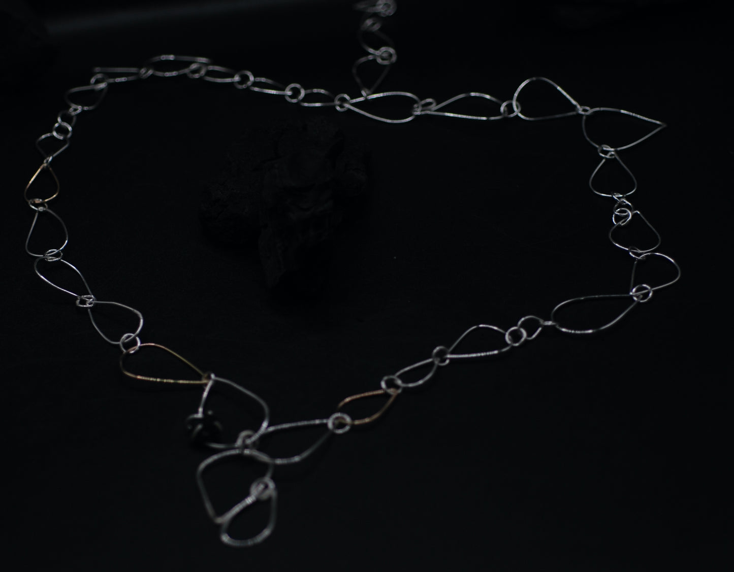 Necklace with siver and golden chains and a small tourmaline gemstone