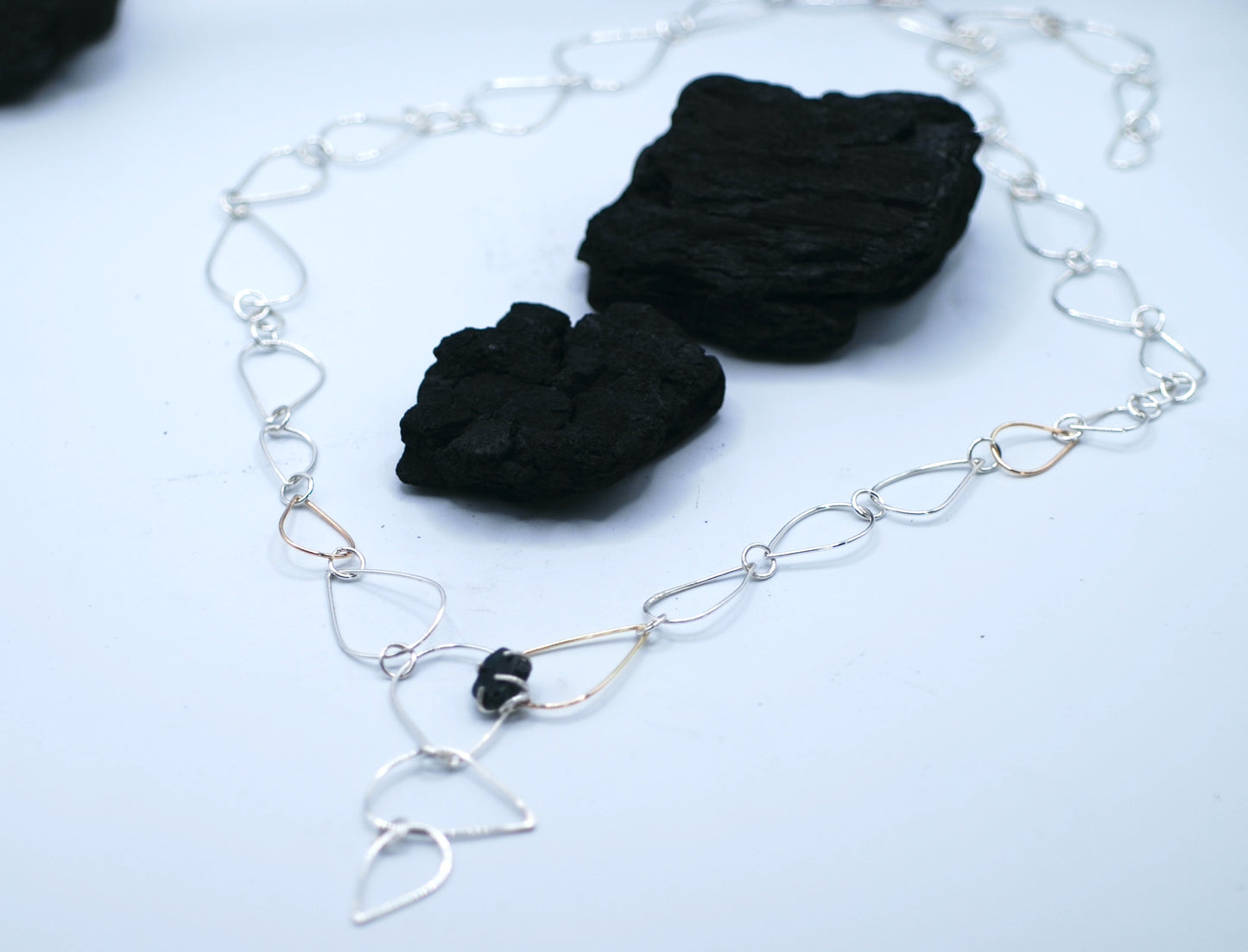 Necklace with siver and golden chains and a small tourmaline gemstone