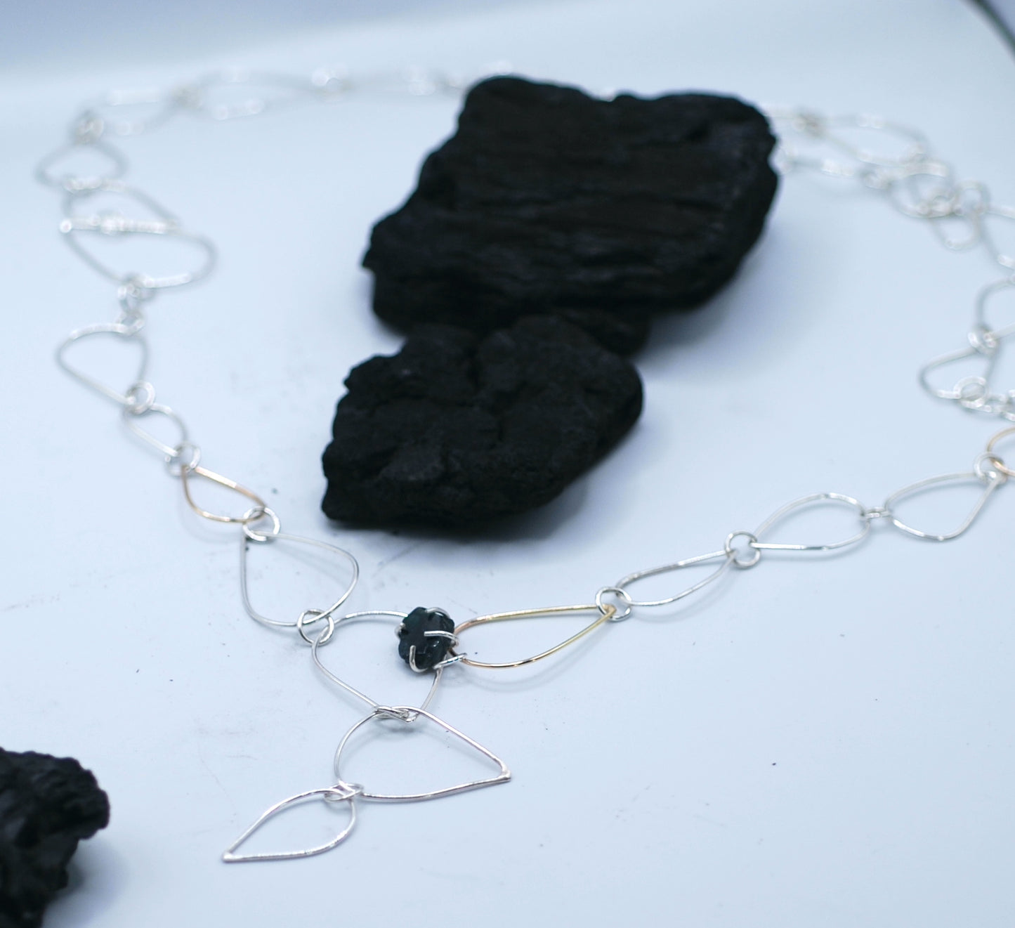 Necklace with siver and golden chains and a small tourmaline gemstone